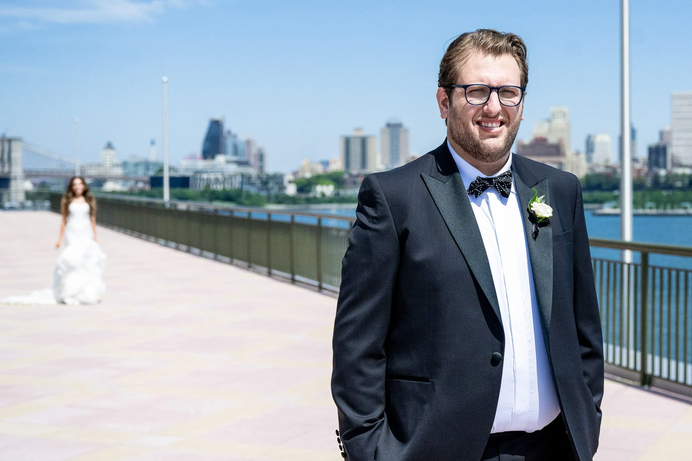 The groom waiting on the waterfront terrace as the bride approaches behind him — Casa Cipriani, New York