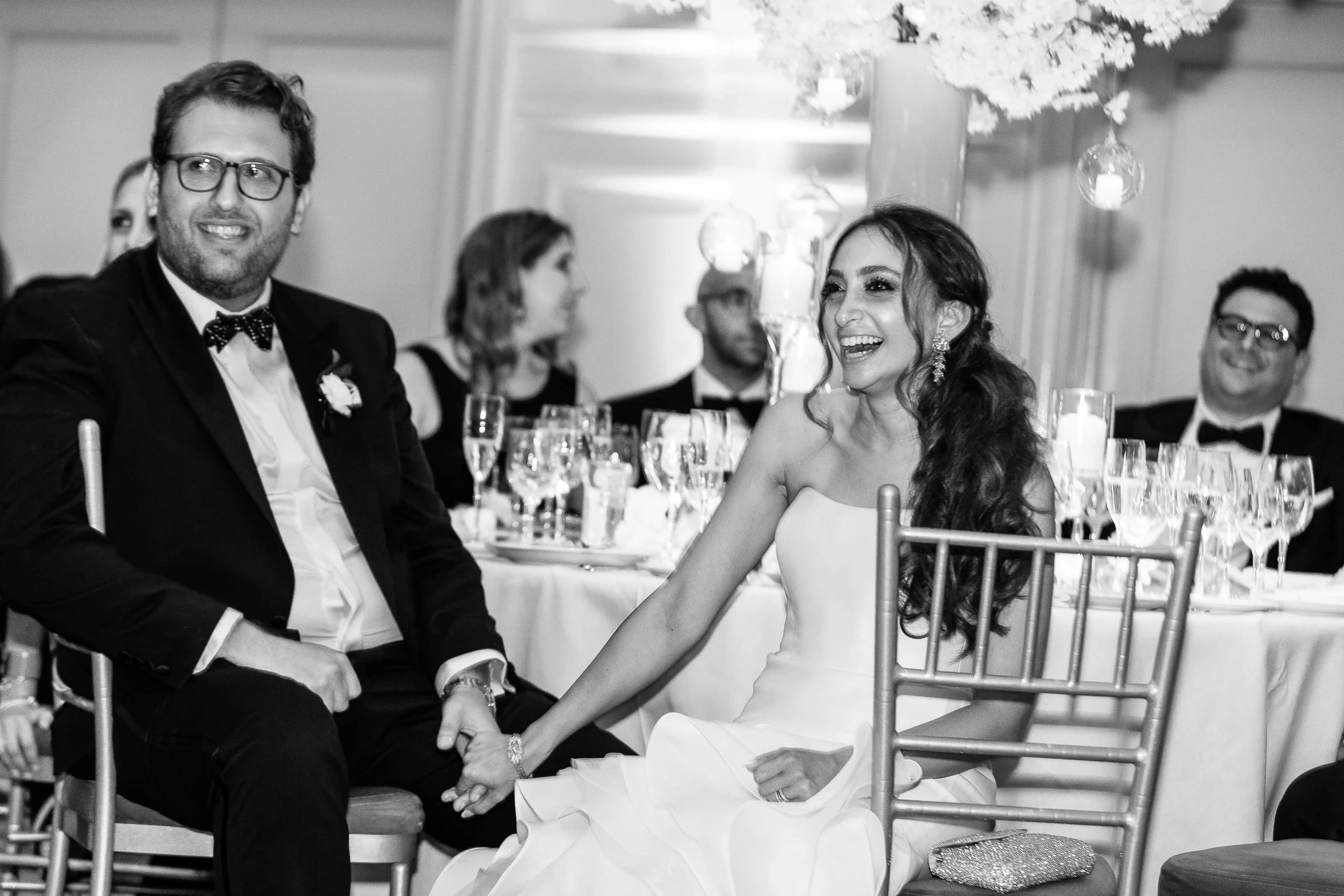 The couple laughing together at their table during the toasts, in black and white — Casa Cipriani, New York