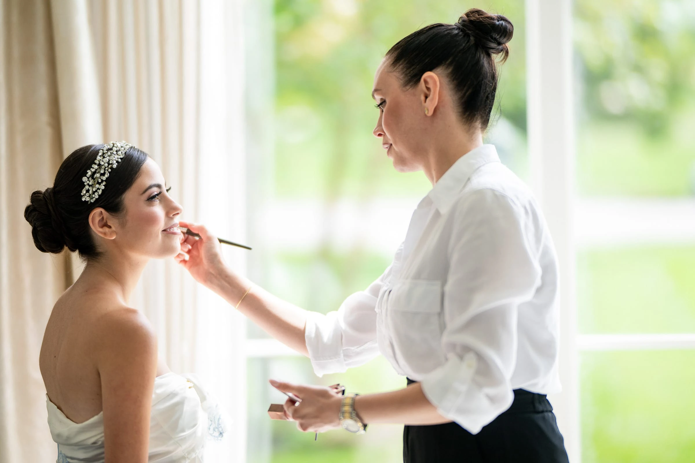 The bride's makeup finished in the window light — Shadowbrook at Shrewsbury, Shrewsbury
