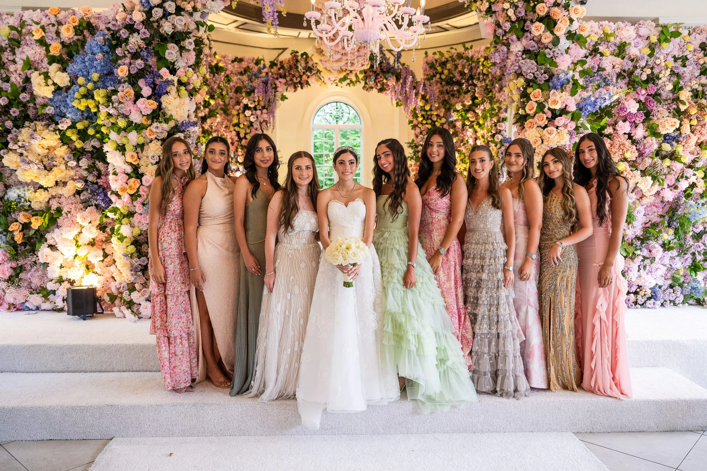 The bride and her bridesmaids in pastel gowns before the flower wall — Shadowbrook at Shrewsbury, Shrewsbury