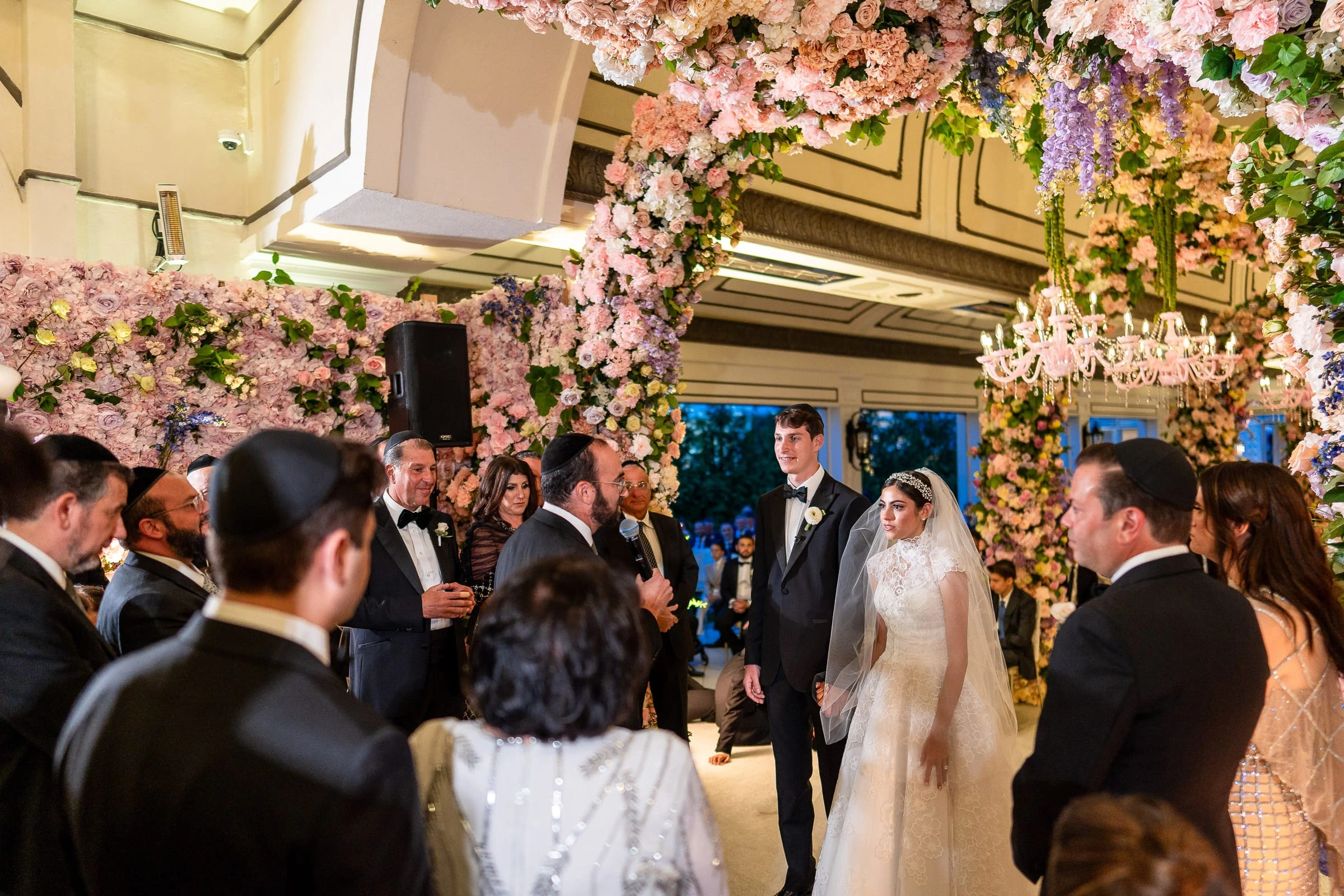 The bride and groom arriving at the flower-covered ceremony arch among their guests — Shadowbrook at Shrewsbury, Shrewsbury