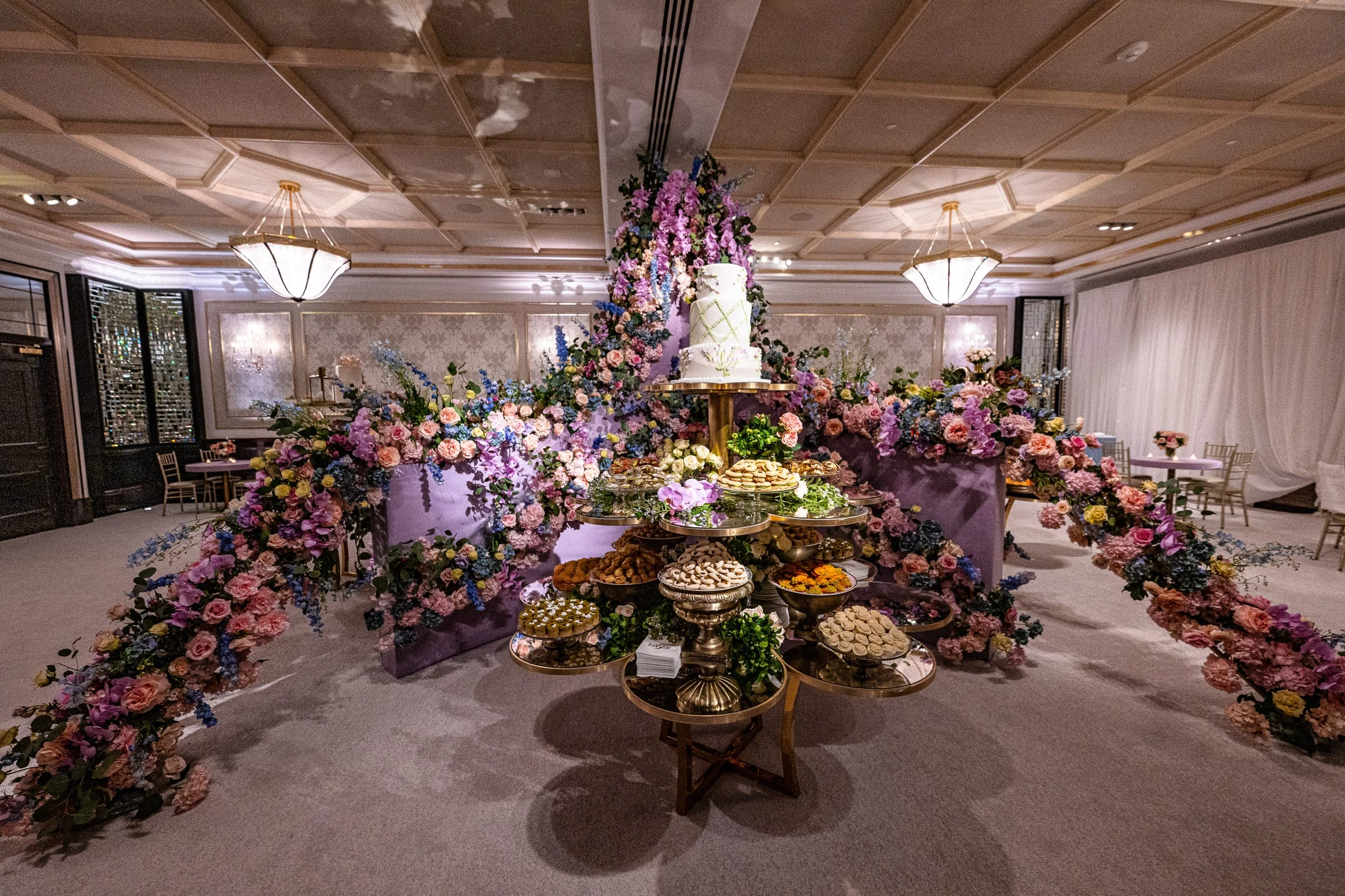The dessert display beneath a cake and trailing pastel flowers in the ballroom — Shadowbrook at Shrewsbury, Shrewsbury