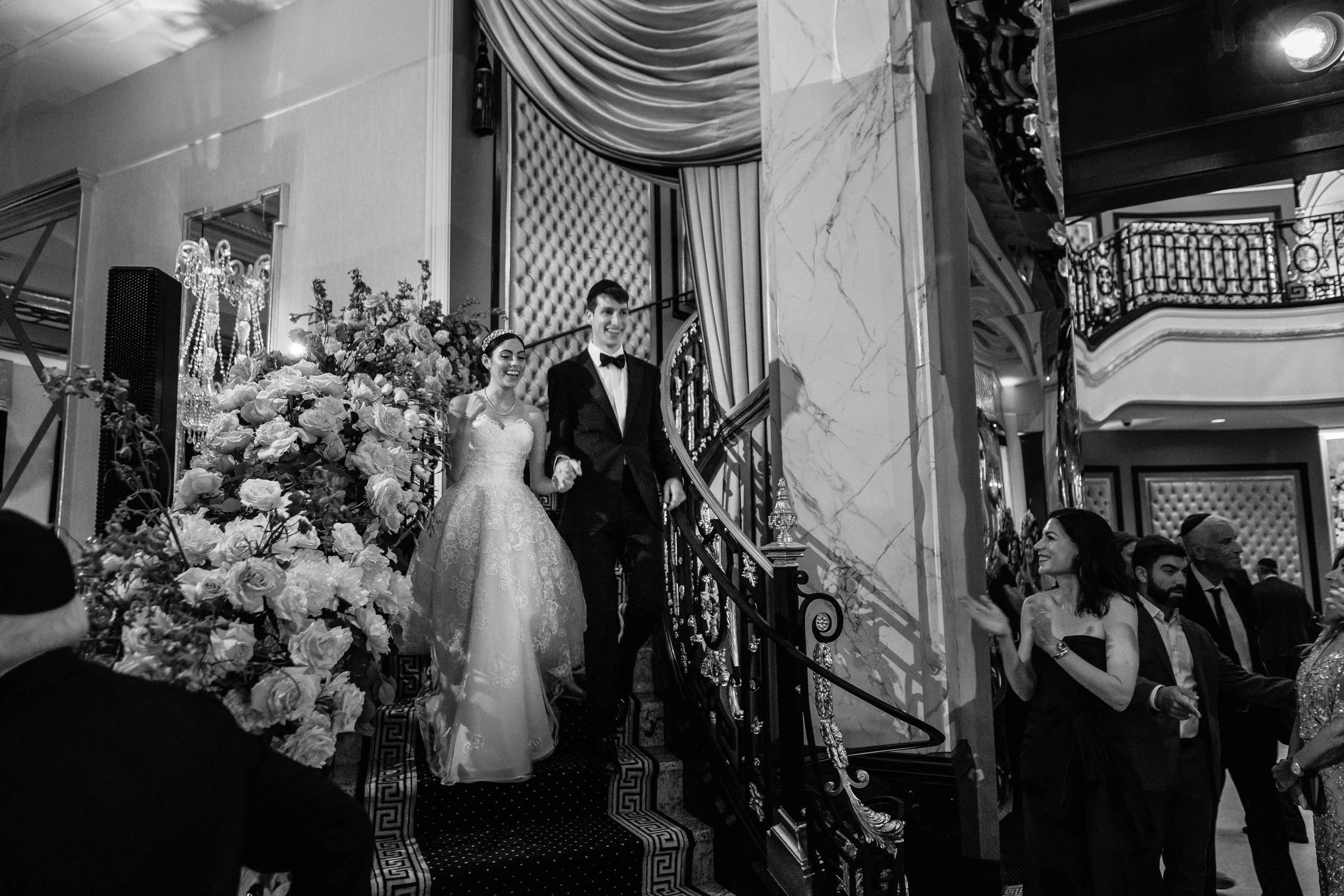 The bride and groom making their entrance down a flower-lined staircase, in black and white — Shadowbrook at Shrewsbury, Shrewsbury