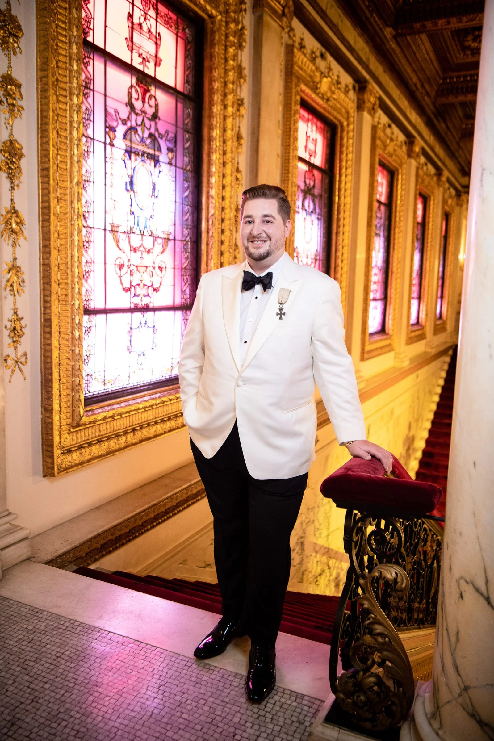 A groom on the club stairs beside the stained glass — Metropolitan Club, New York