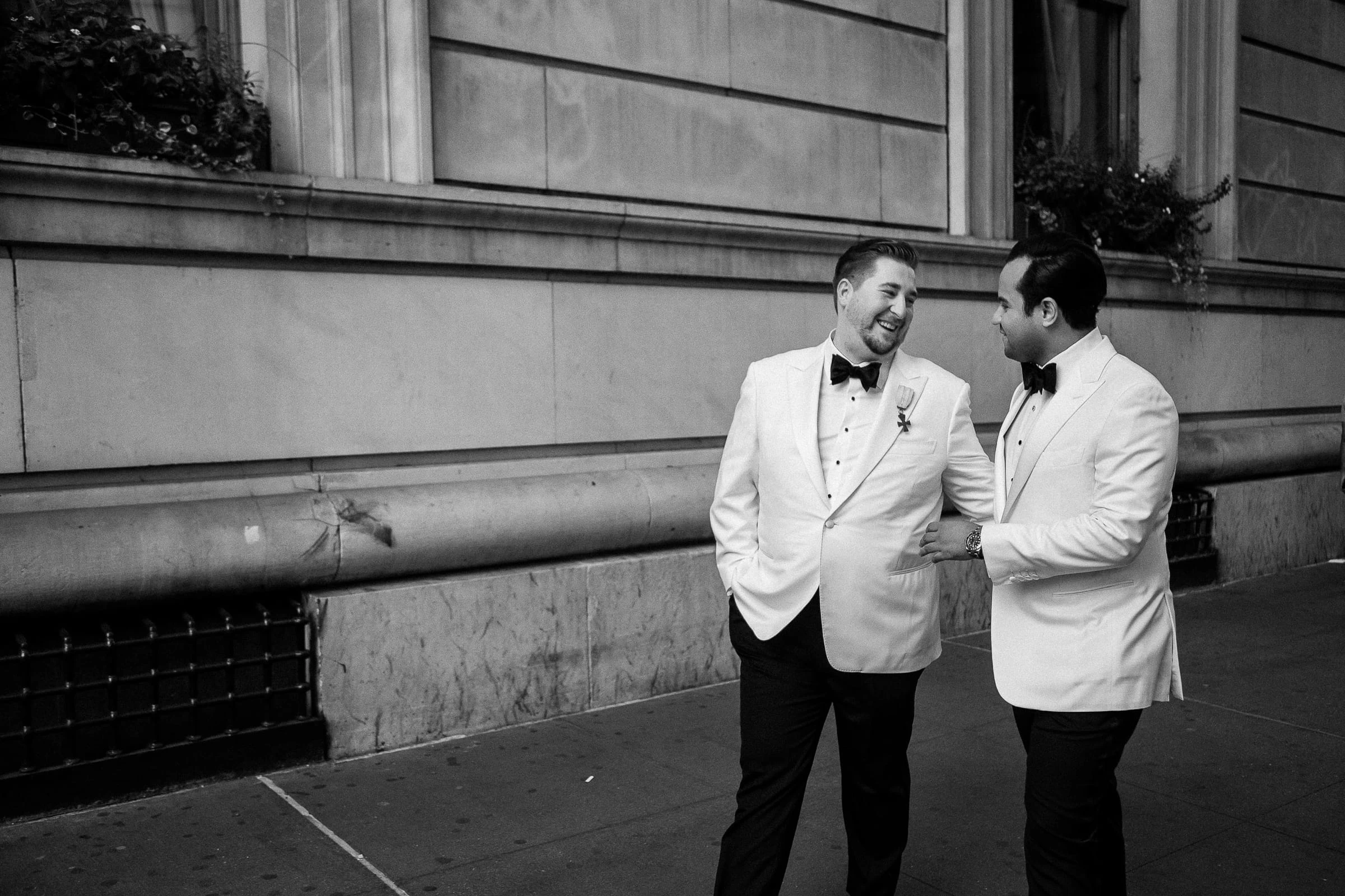 The grooms on the sidewalk outside the club, in black and white — Metropolitan Club, New York