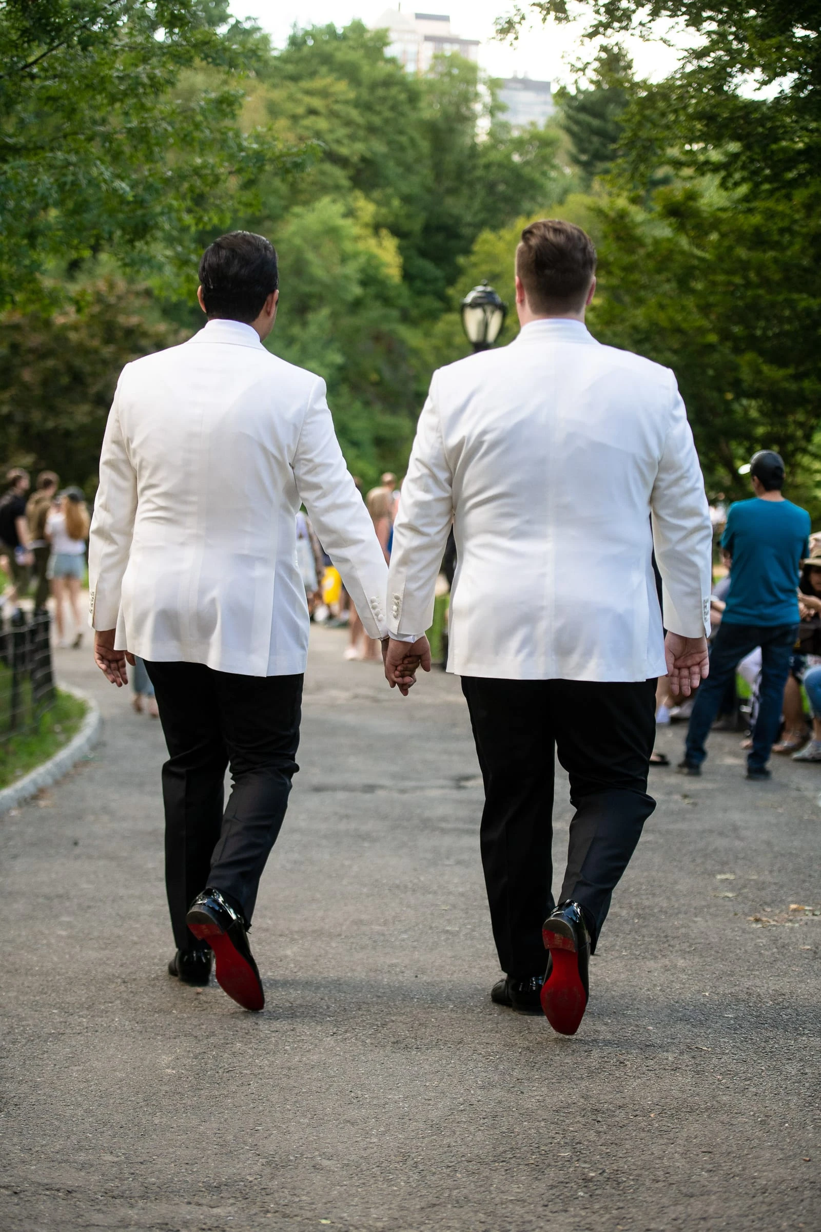 The grooms walking away hand in hand, red soles showing — Metropolitan Club, New York