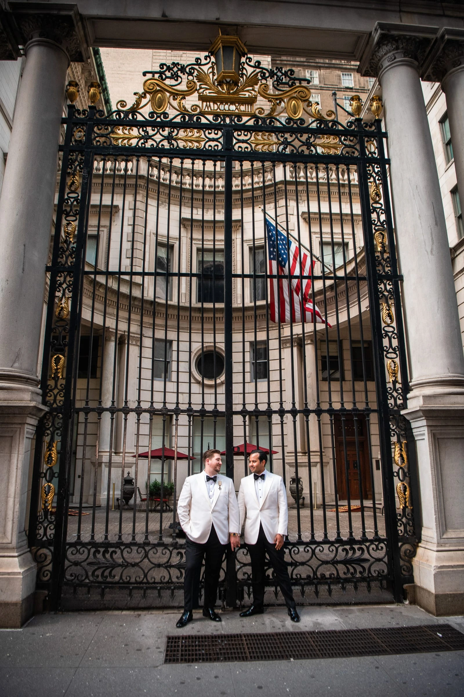 The grooms framed in the club's iron gates — Metropolitan Club, New York