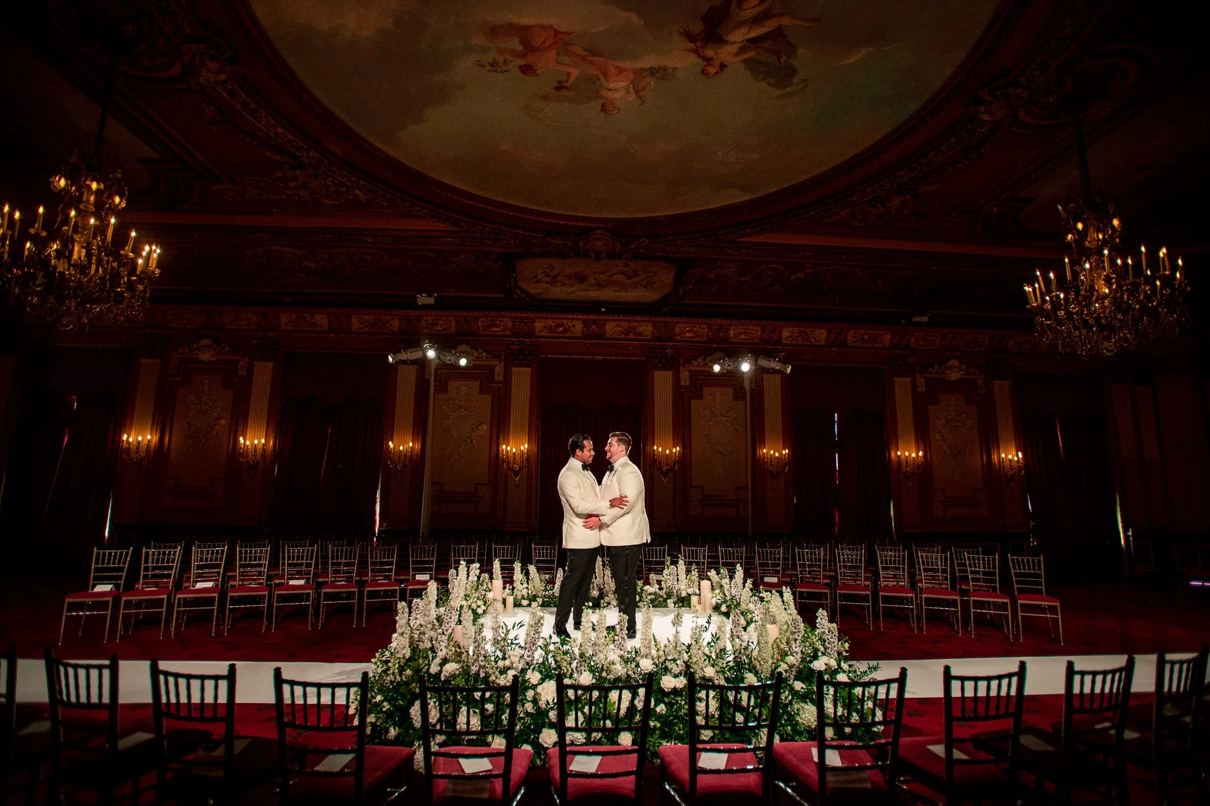 The grooms alone in the empty ceremony room beneath the painted ceiling — Metropolitan Club, New York
