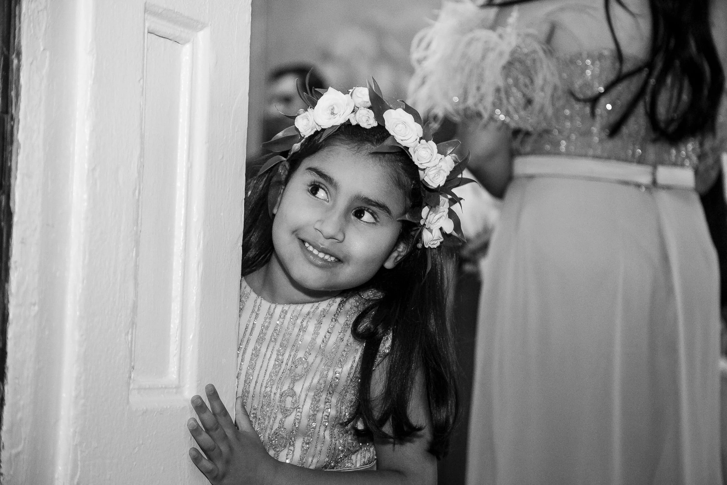 A flower girl peering round the doorframe, in black and white — Metropolitan Club, New York