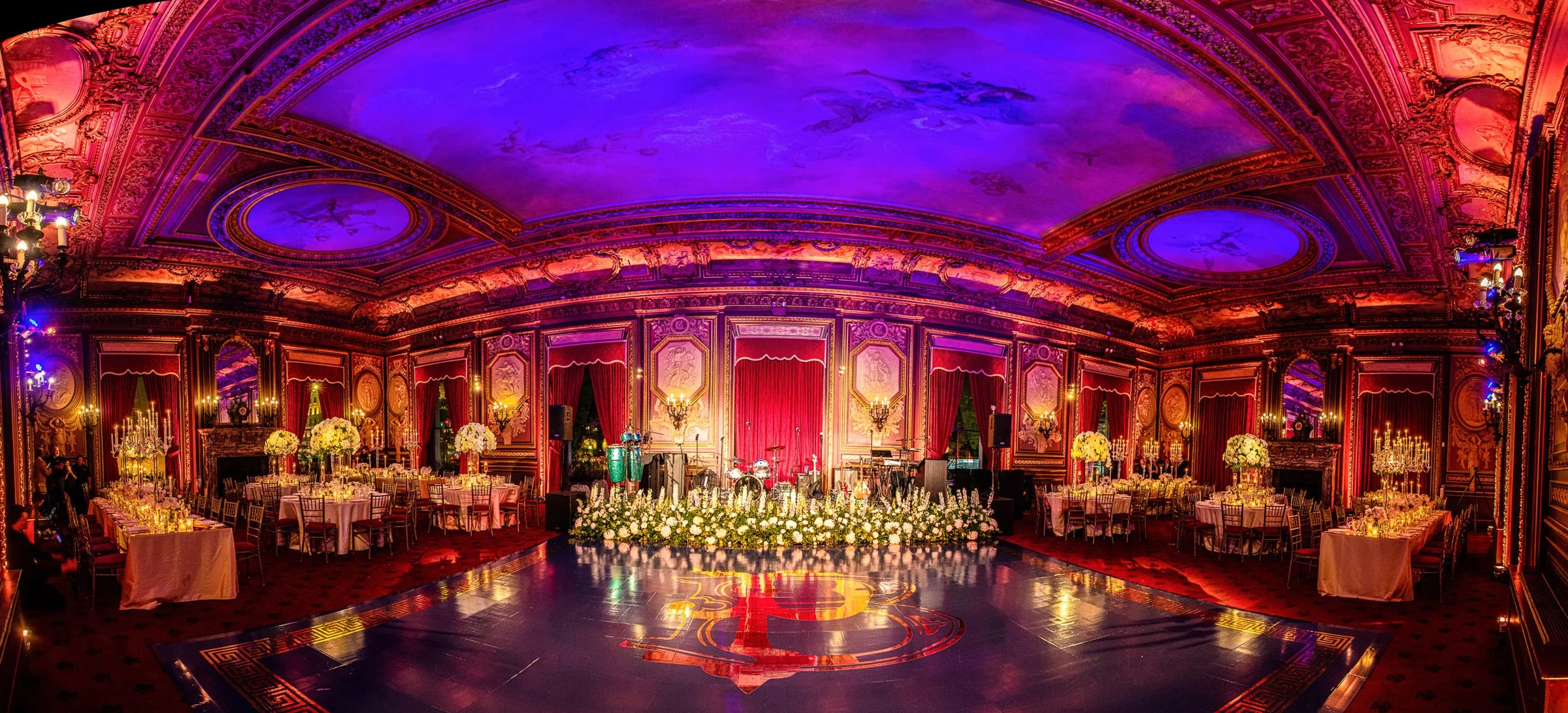 The gilded ballroom in red and violet light, set for dinner around the dance floor — Metropolitan Club, New York