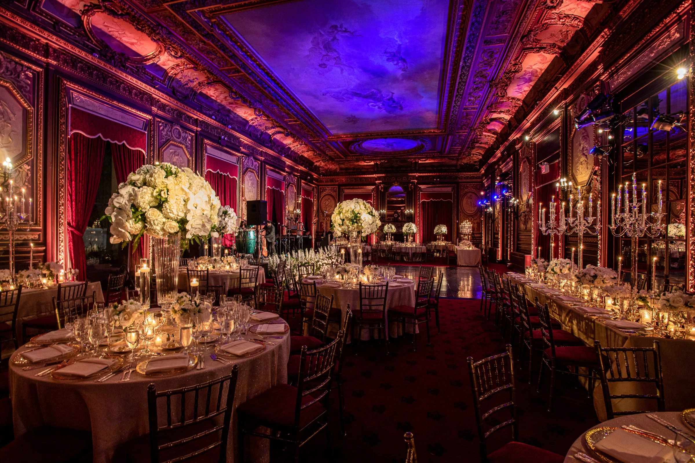 The candlelit dinner tables in the gilded ballroom under a violet-lit ceiling — Metropolitan Club, New York