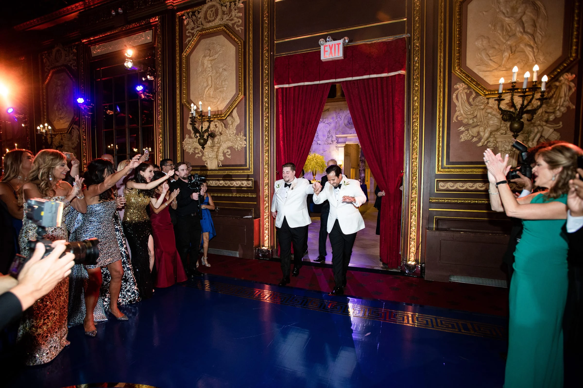 The two grooms entering the ballroom through red curtains as guests cheer — Metropolitan Club, New York