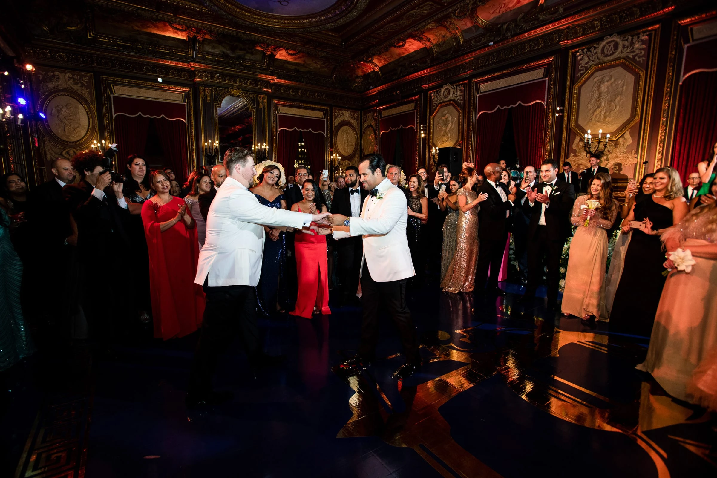 The two grooms dancing hand in hand in front of a crowd of guests — Metropolitan Club, New York