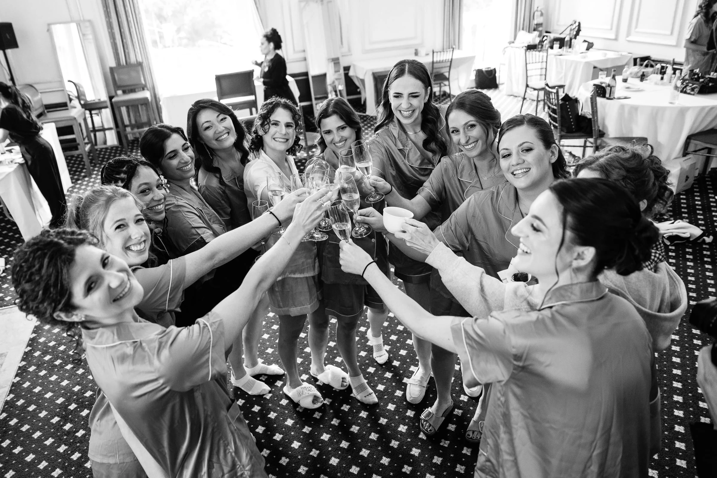 The bride and her friends clinking champagne glasses in their robes, in black and white — Metropolitan Club, New York
