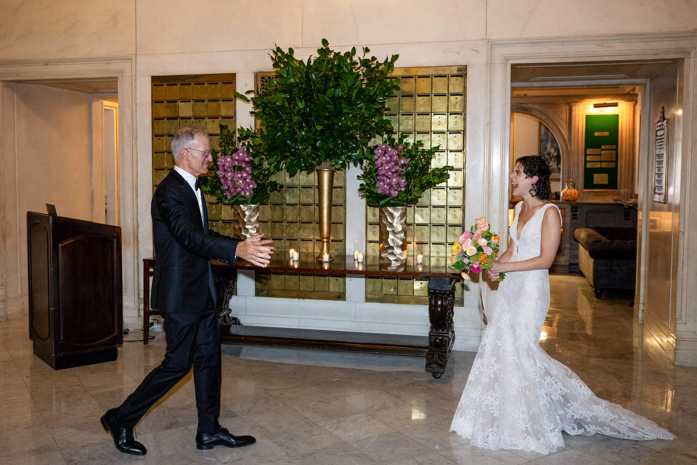 A first look in the marble lobby beneath a tall arrangement of greenery — Metropolitan Club, New York