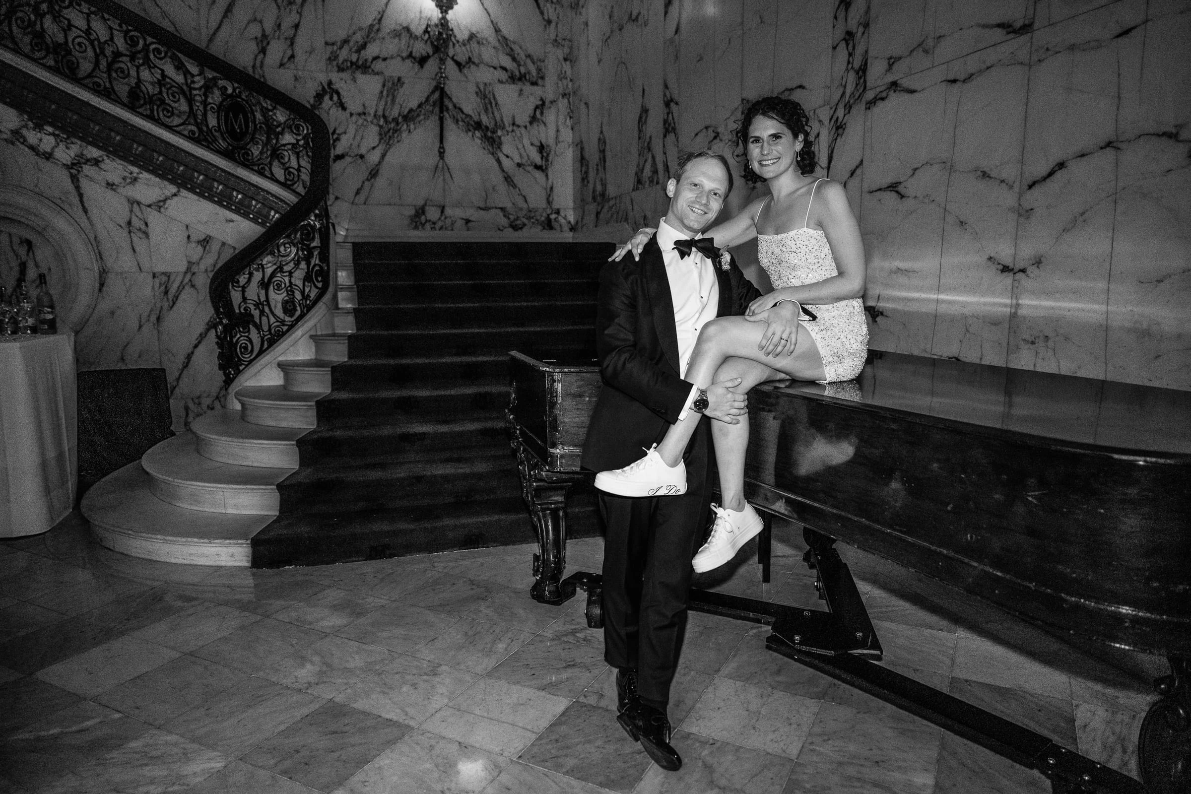 The groom carrying the bride at the foot of the marble staircase, in black and white — Metropolitan Club, New York
