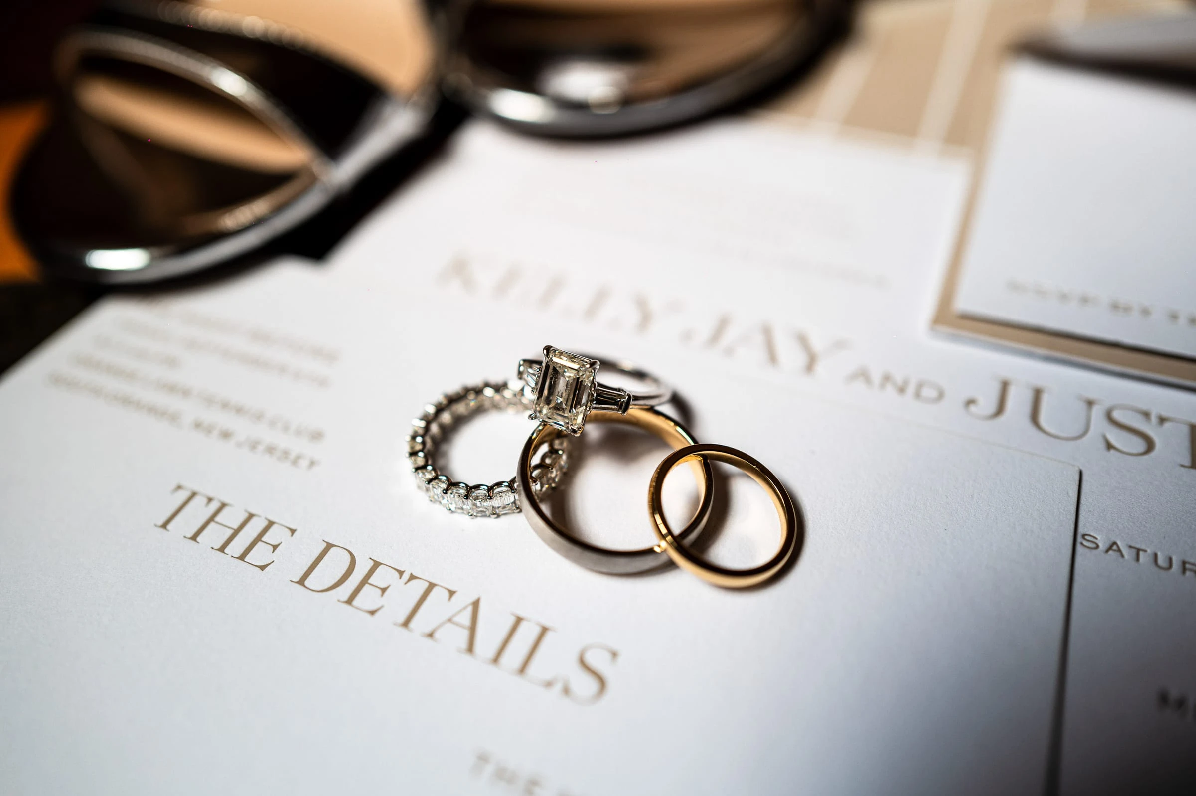 The wedding rings resting on the invitation suite — Mountain Ridge Country Club, West Caldwell