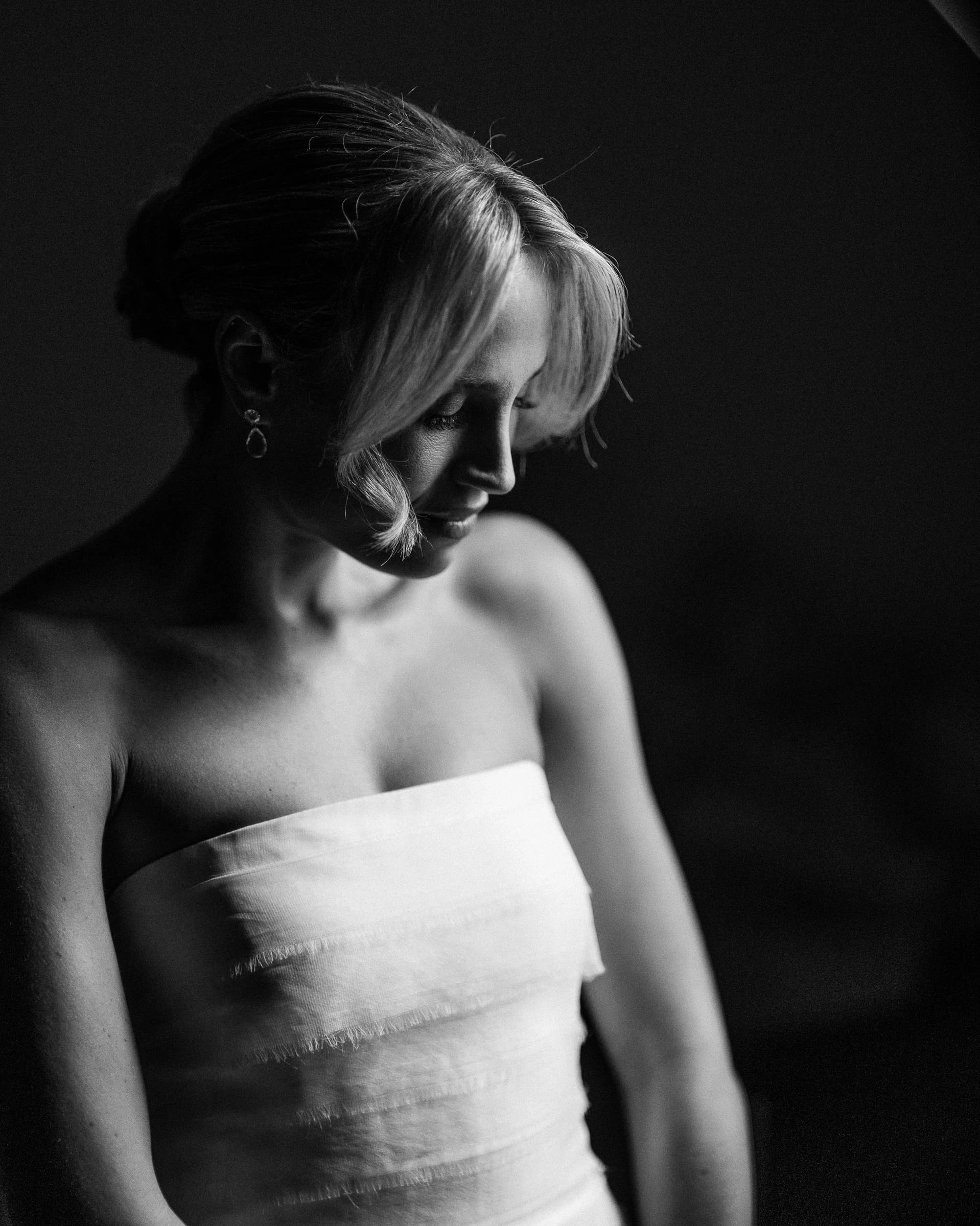 A quiet portrait of the bride looking down against a dark backdrop, in black and white — Mountain Ridge Country Club, West Caldwell