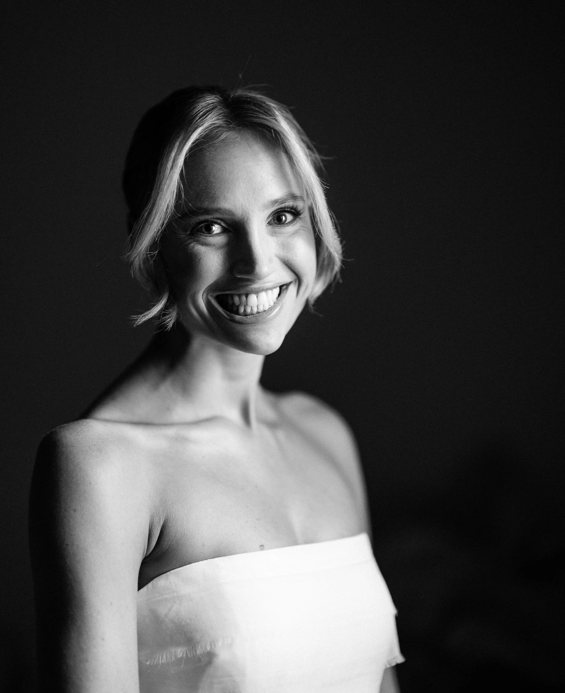 The bride smiling in a portrait against a dark backdrop, in black and white — Mountain Ridge Country Club, West Caldwell