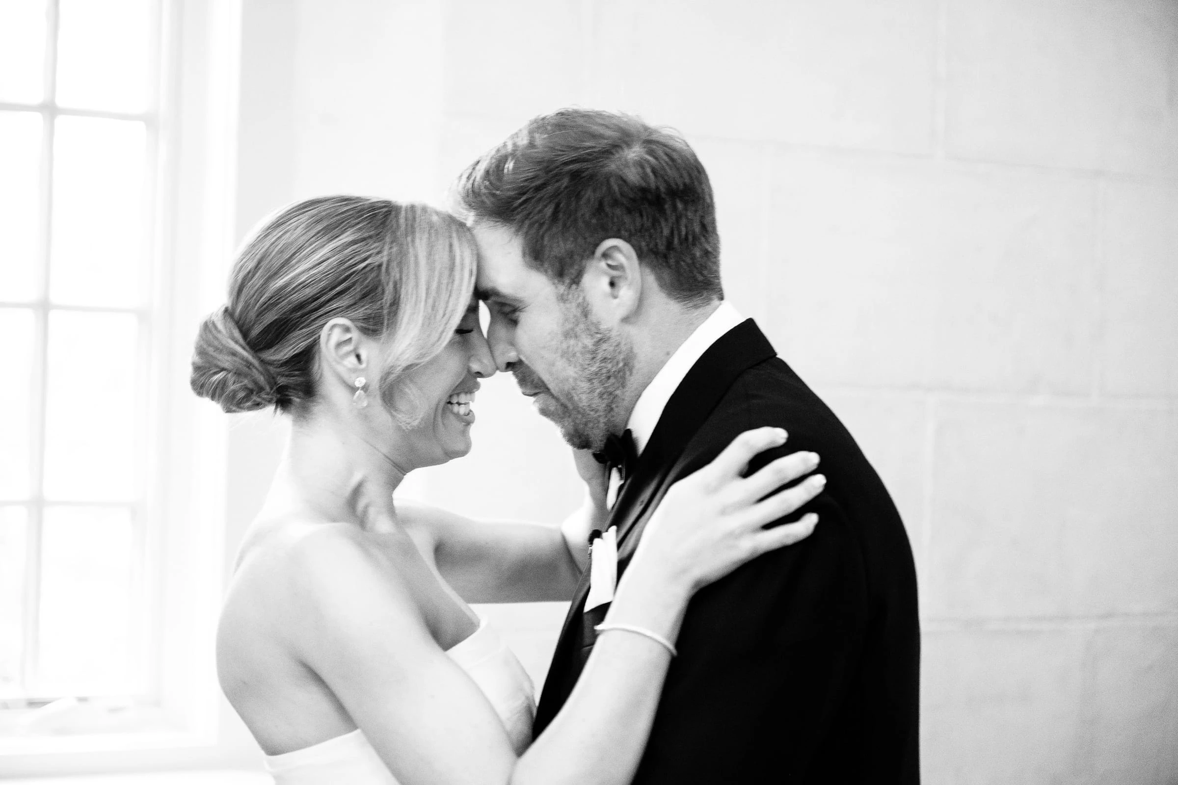 The couple forehead to forehead in the window light, in black and white — Mountain Ridge Country Club, West Caldwell