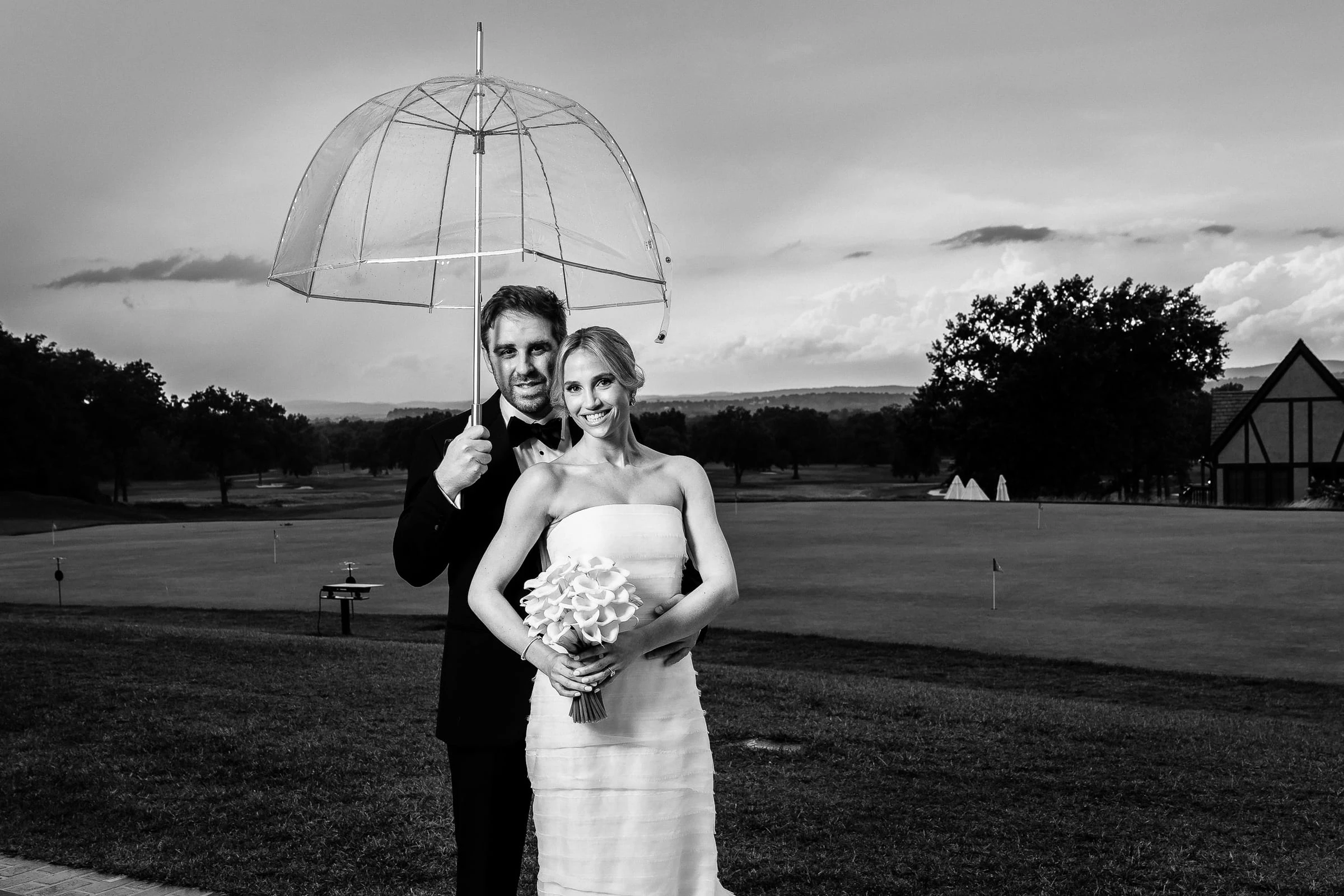 The couple under a clear umbrella out on the course, in black and white — Mountain Ridge Country Club, West Caldwell
