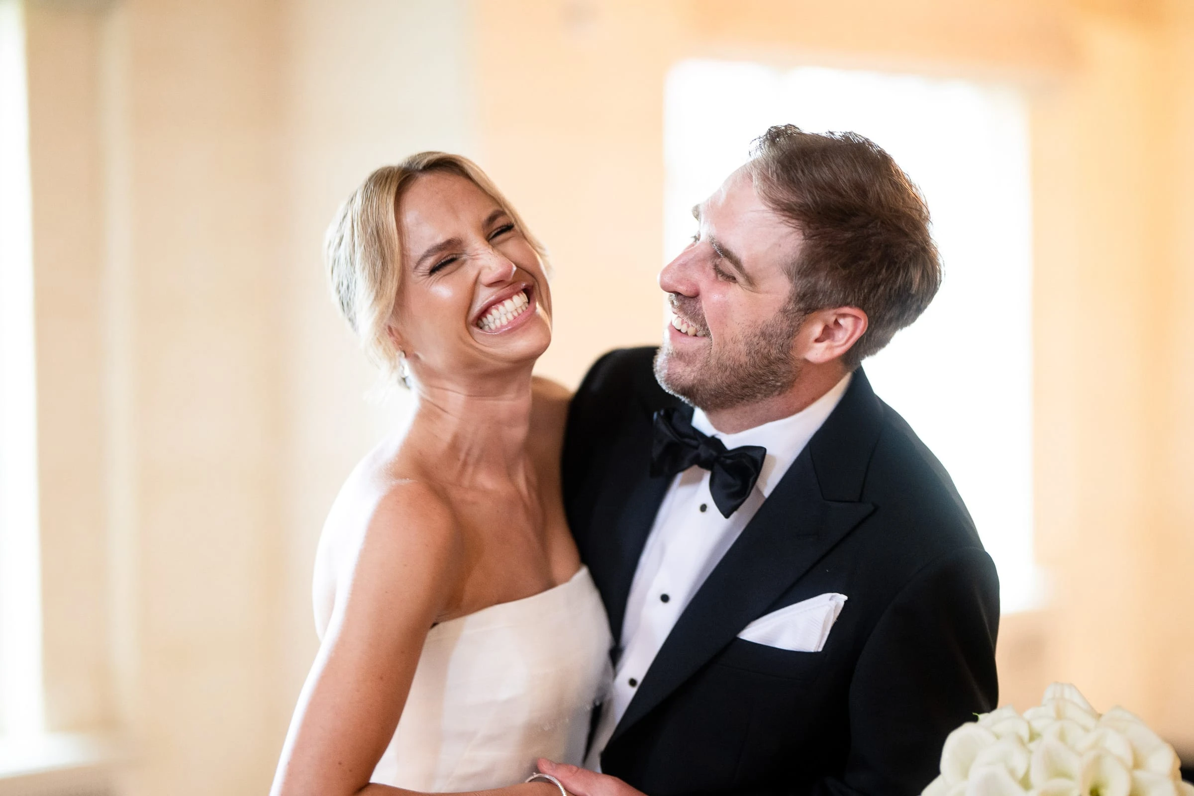The bride laughing against the groom's shoulder in the afternoon light — Mountain Ridge Country Club, West Caldwell