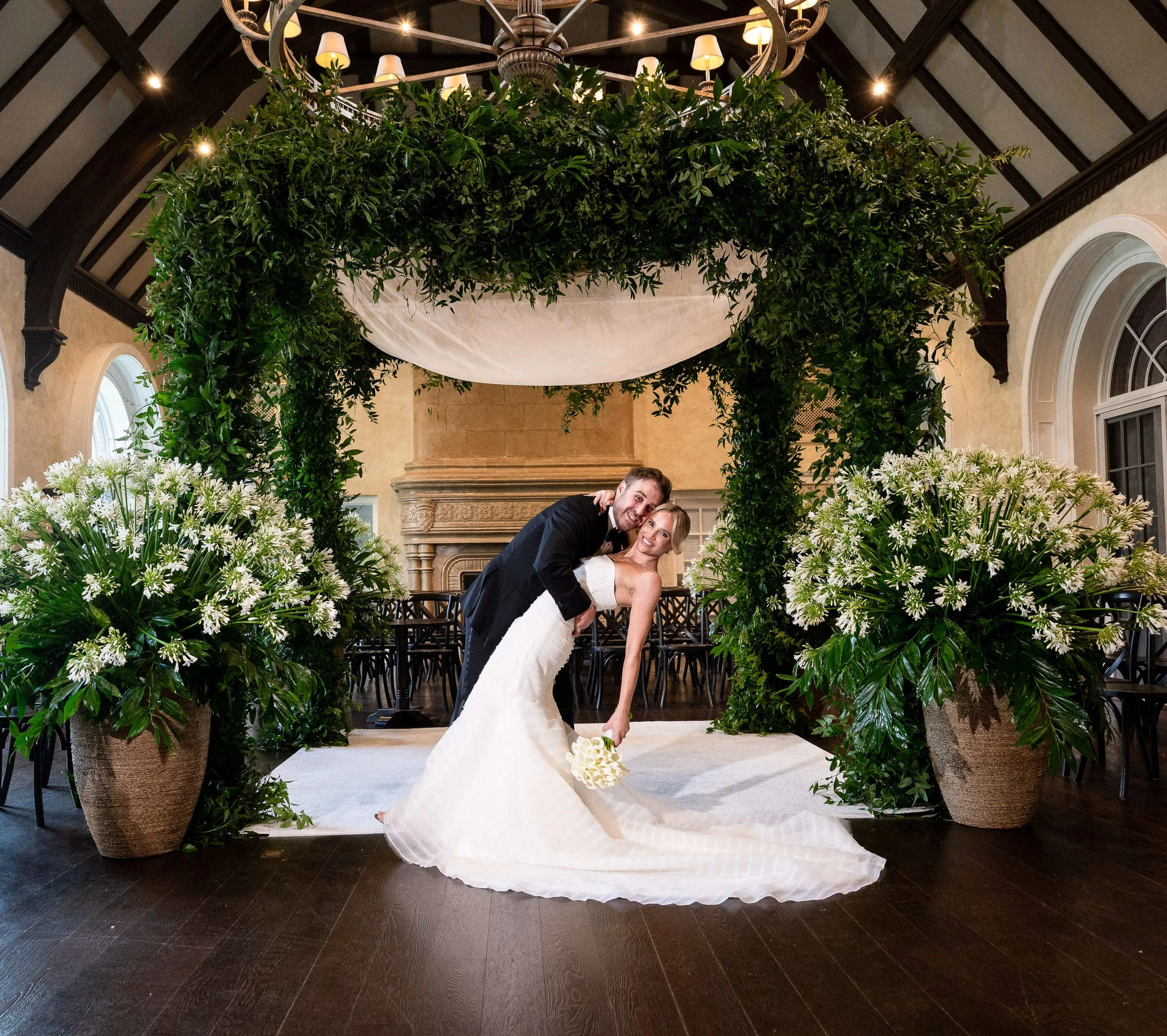 The couple dipping beneath a chuppah covered in greenery — Mountain Ridge Country Club, West Caldwell