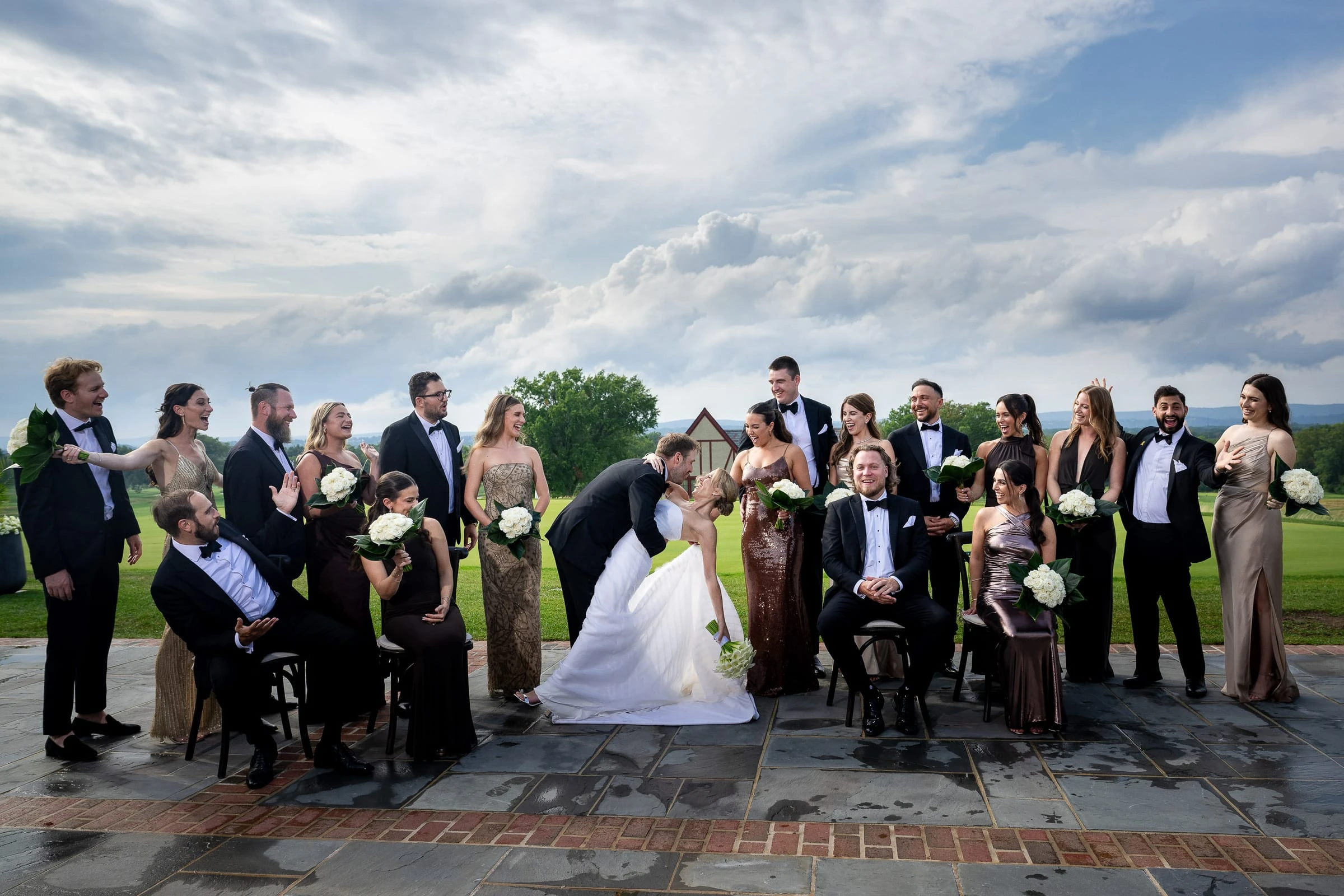 The wedding party on the terrace as the couple kiss in the middle — Mountain Ridge Country Club, West Caldwell