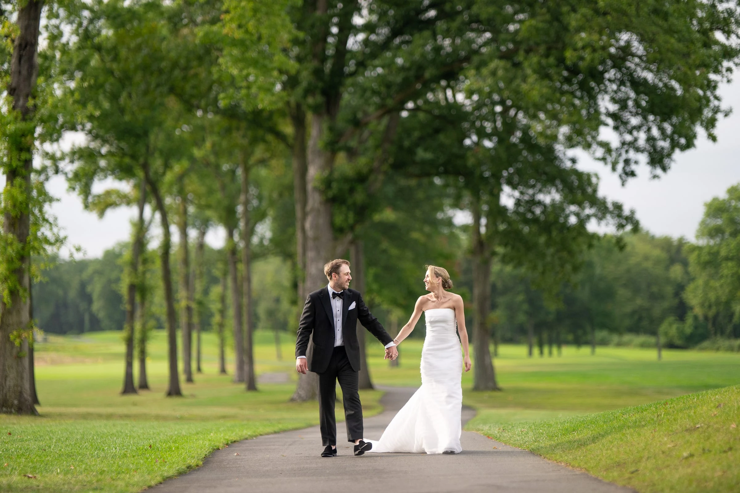 The couple walking hand in hand down the tree-lined cart path — Mountain Ridge Country Club, West Caldwell