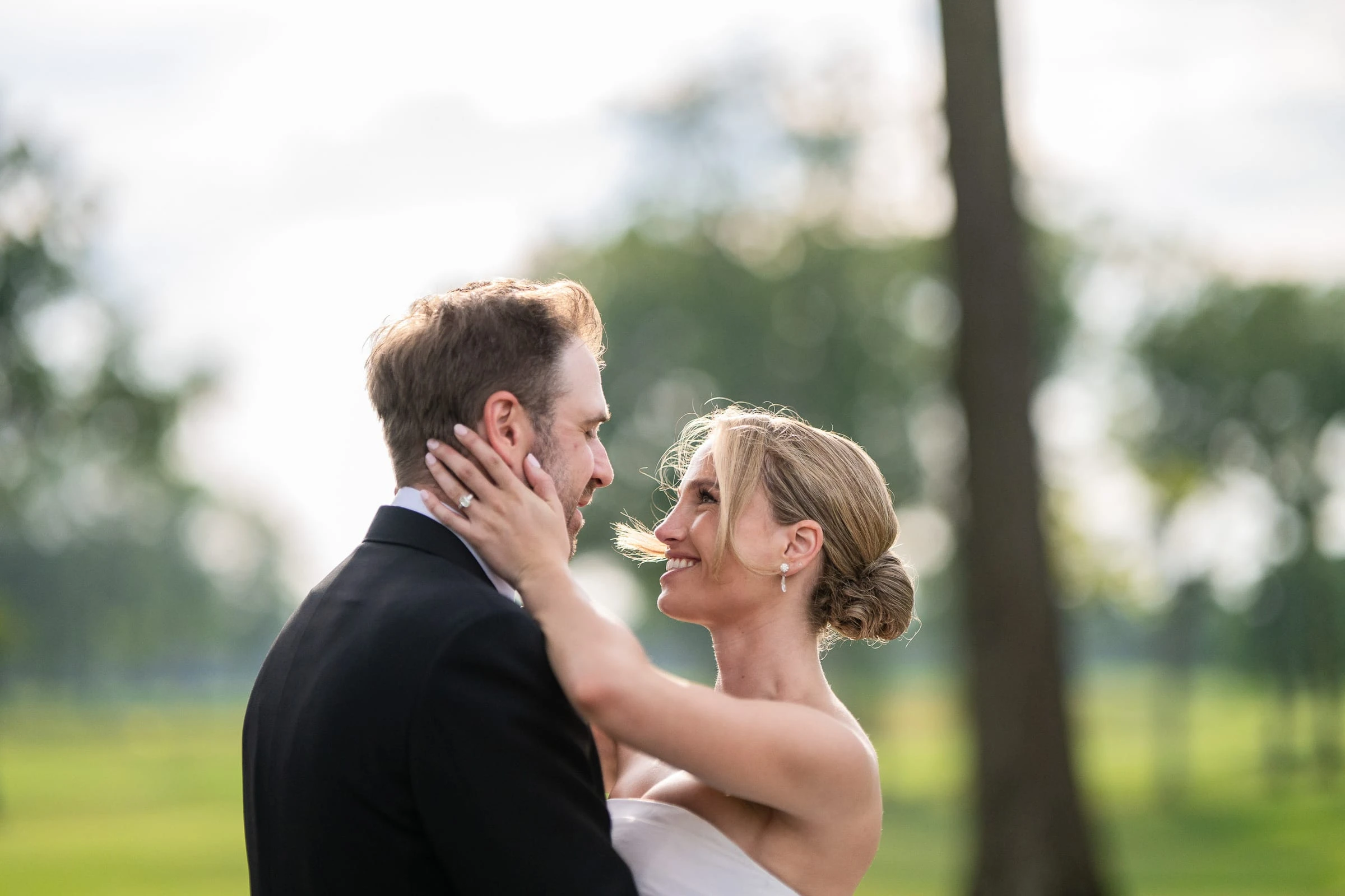 The bride holding the groom's face in the low evening sun — Mountain Ridge Country Club, West Caldwell