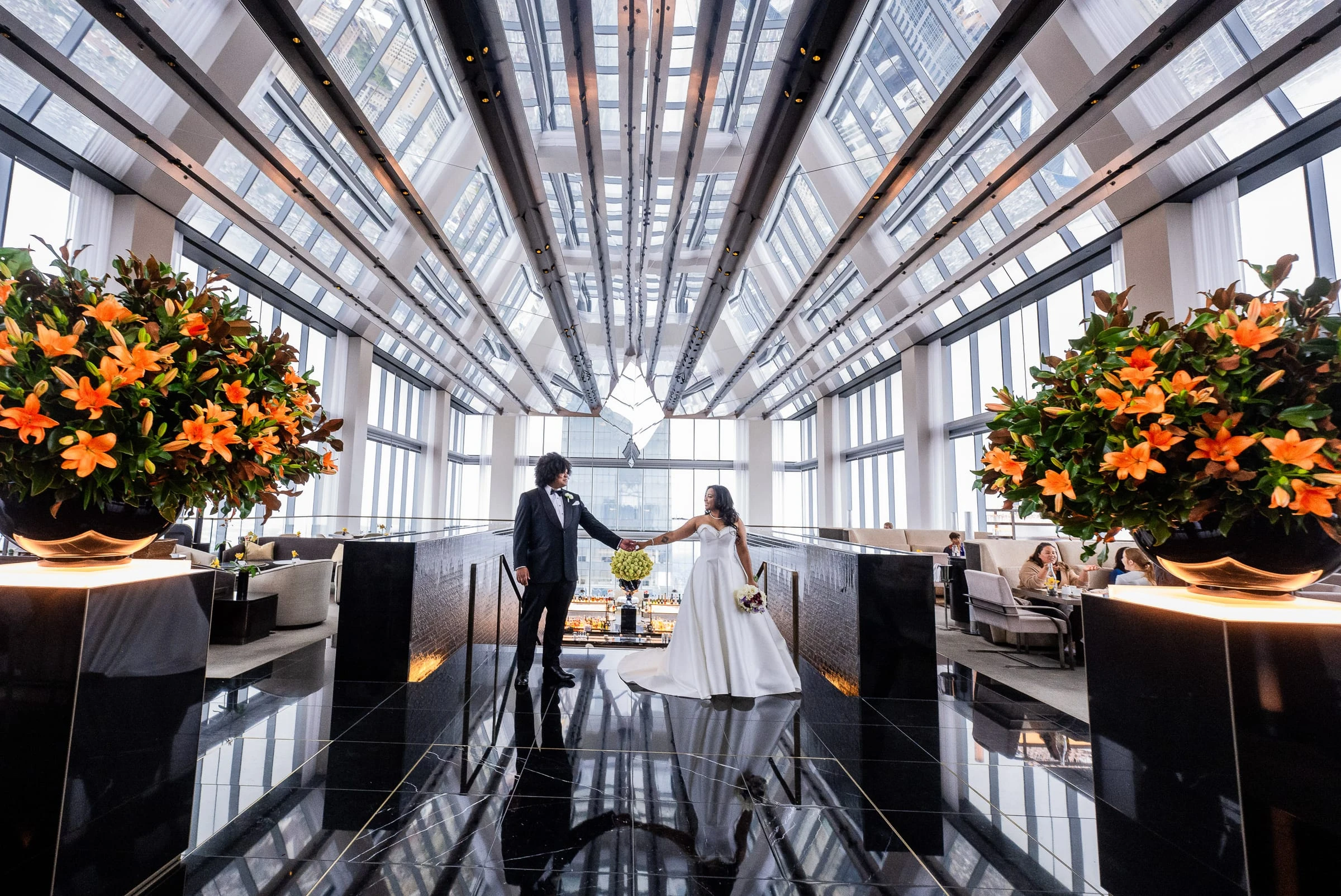 The couple in the glass-roofed atrium between urns of orange lilies — Philadelphia Museum of Art, Philadelphia