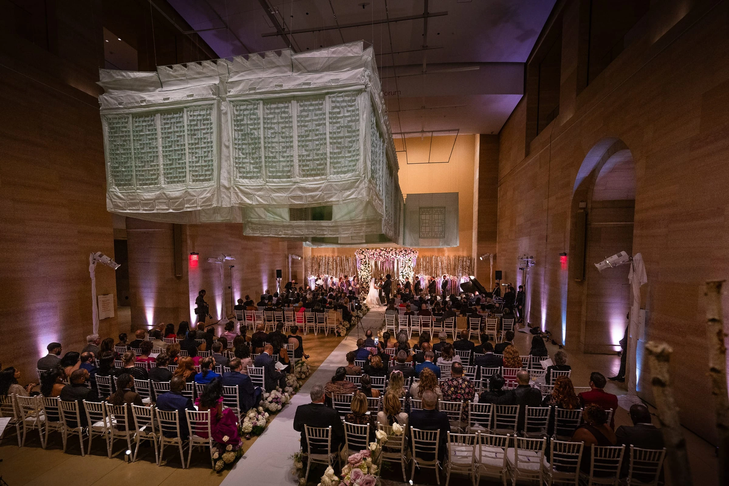 The ceremony in the stone hall beneath the hanging glass panels — Philadelphia Museum of Art, Philadelphia