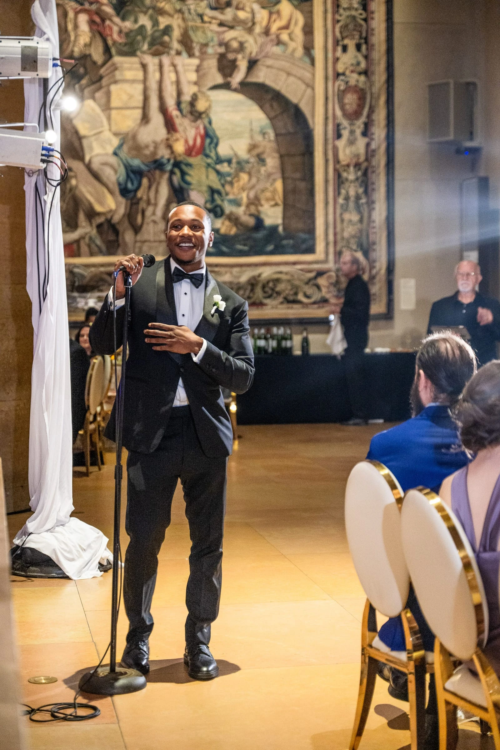 A toast at the microphone beneath a large tapestry — Philadelphia Museum of Art, Philadelphia