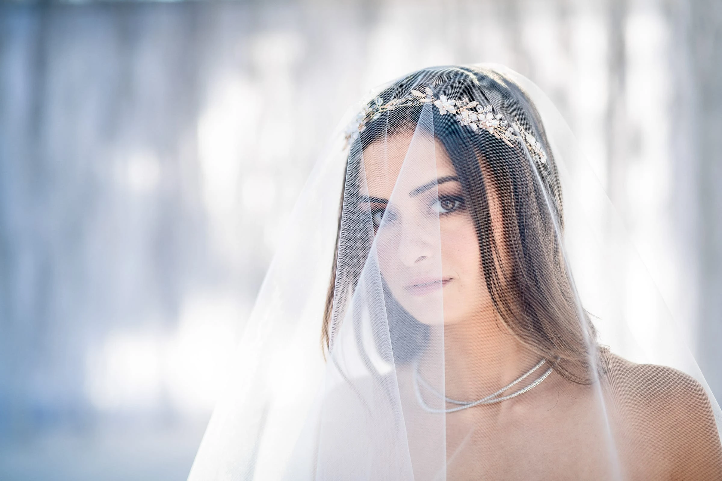 A close portrait of a bride looking through her sheer veil in soft window light