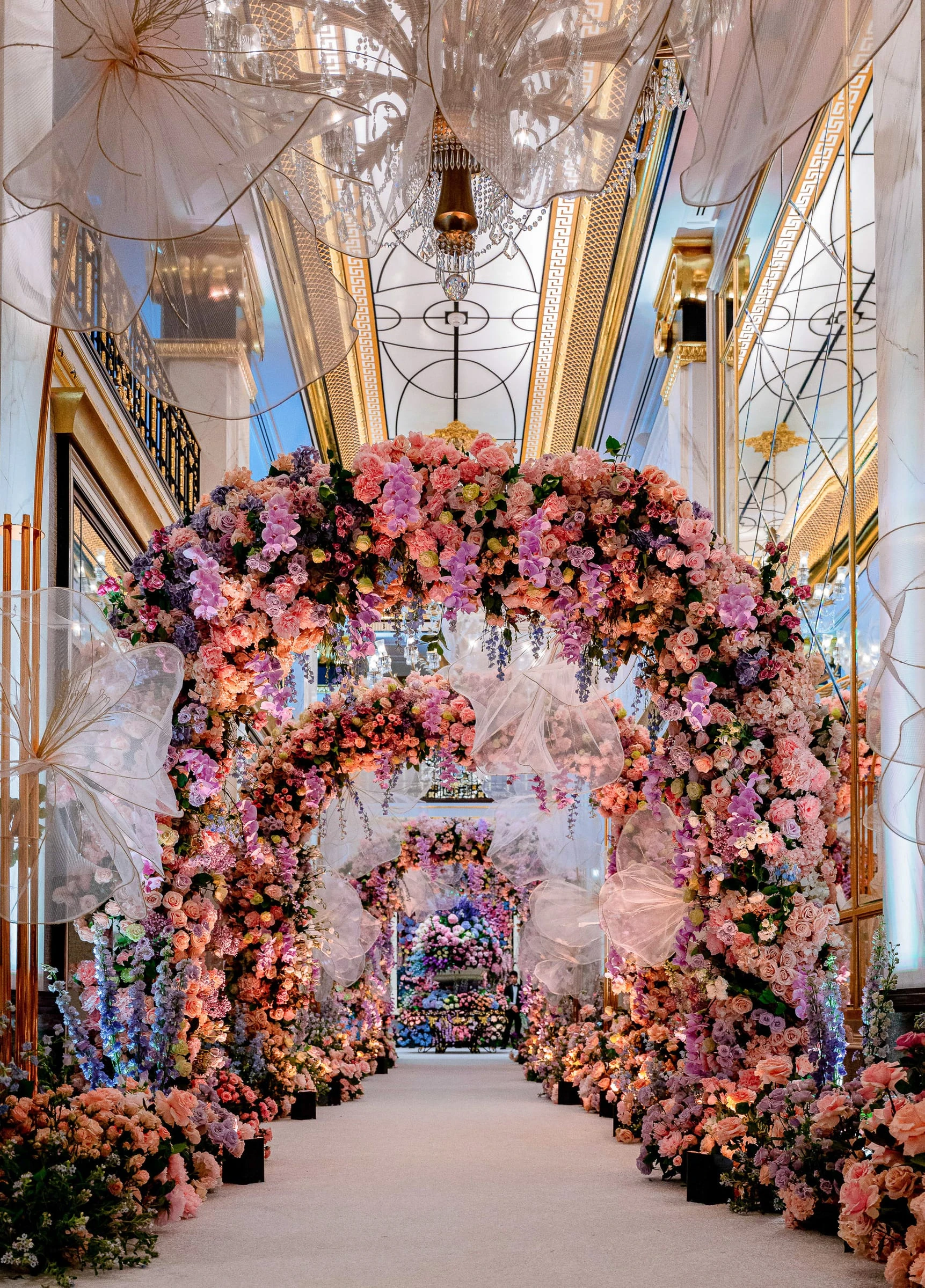 A tunnel of dense pink and coral flowers arching the length of the ceremony aisle