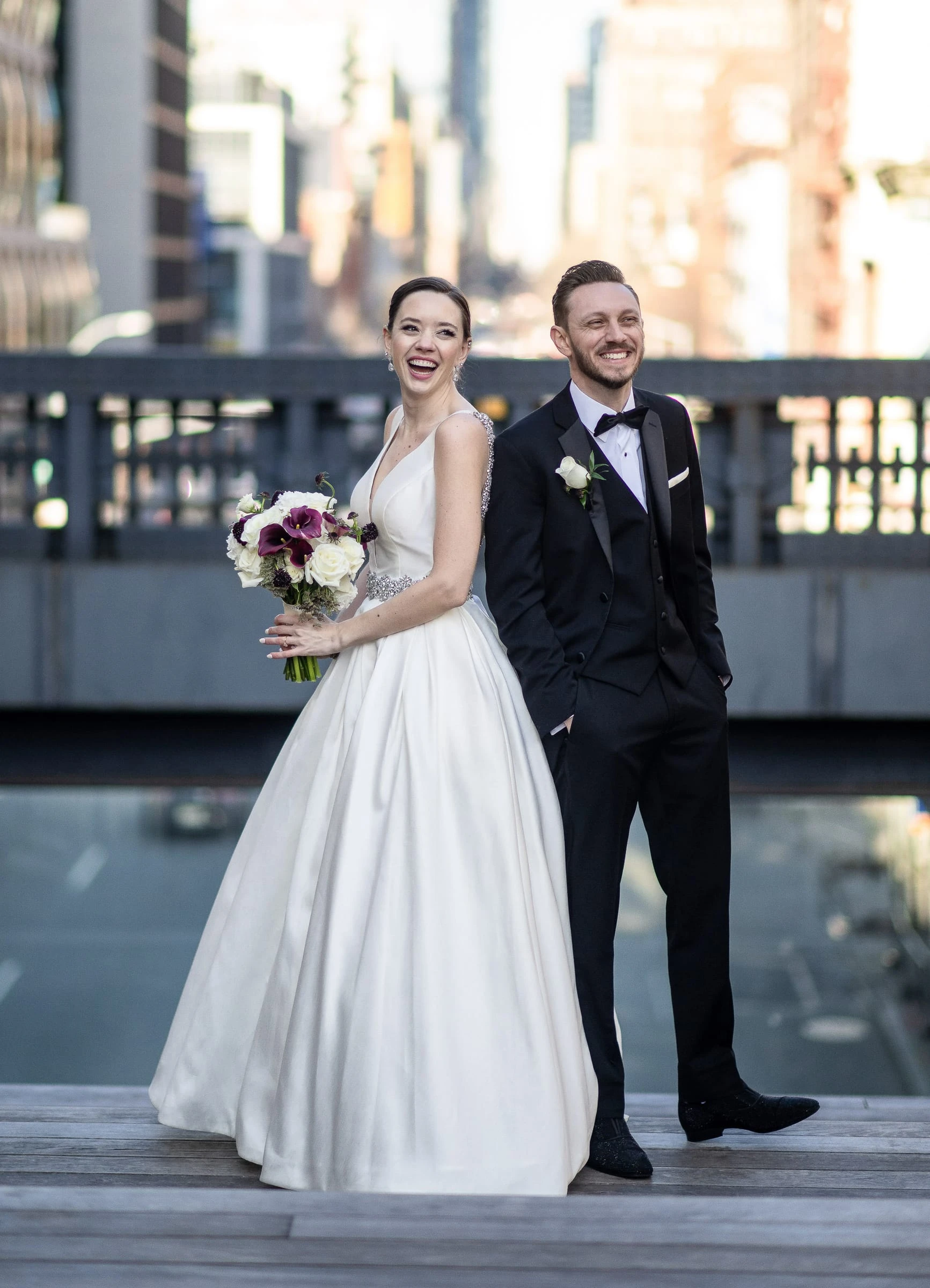 A couple standing together on a rooftop with the city skyline behind them