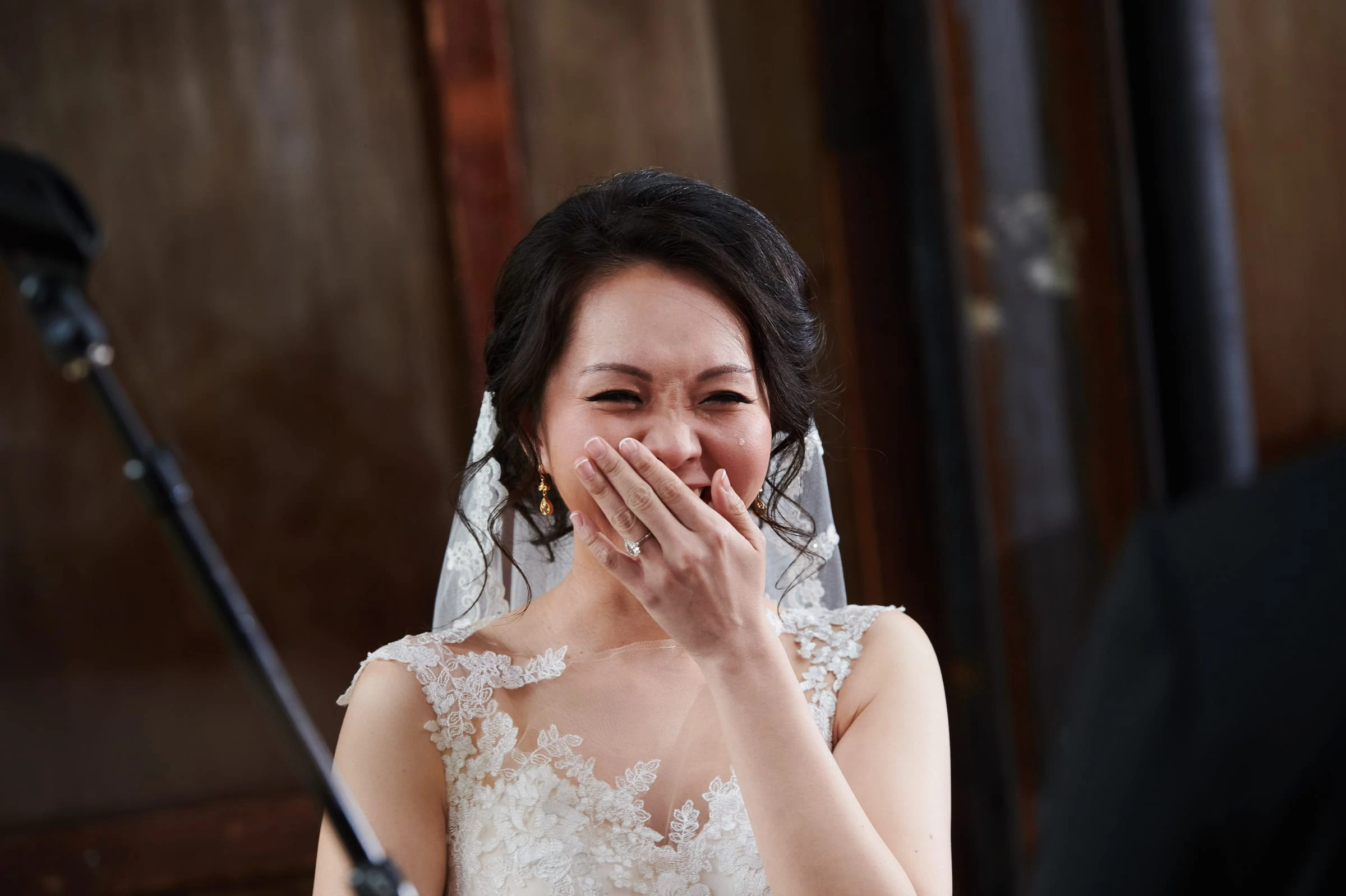A bride laughing behind her hand during the ceremony