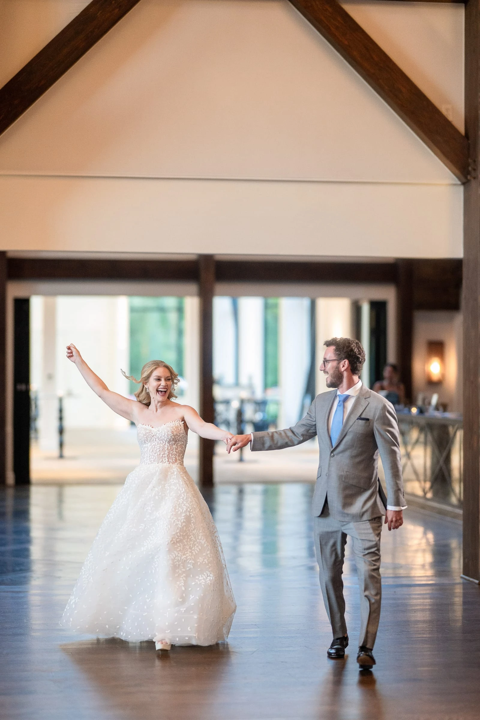 A bride and groom mid-turn in their first dance in a beamed room
