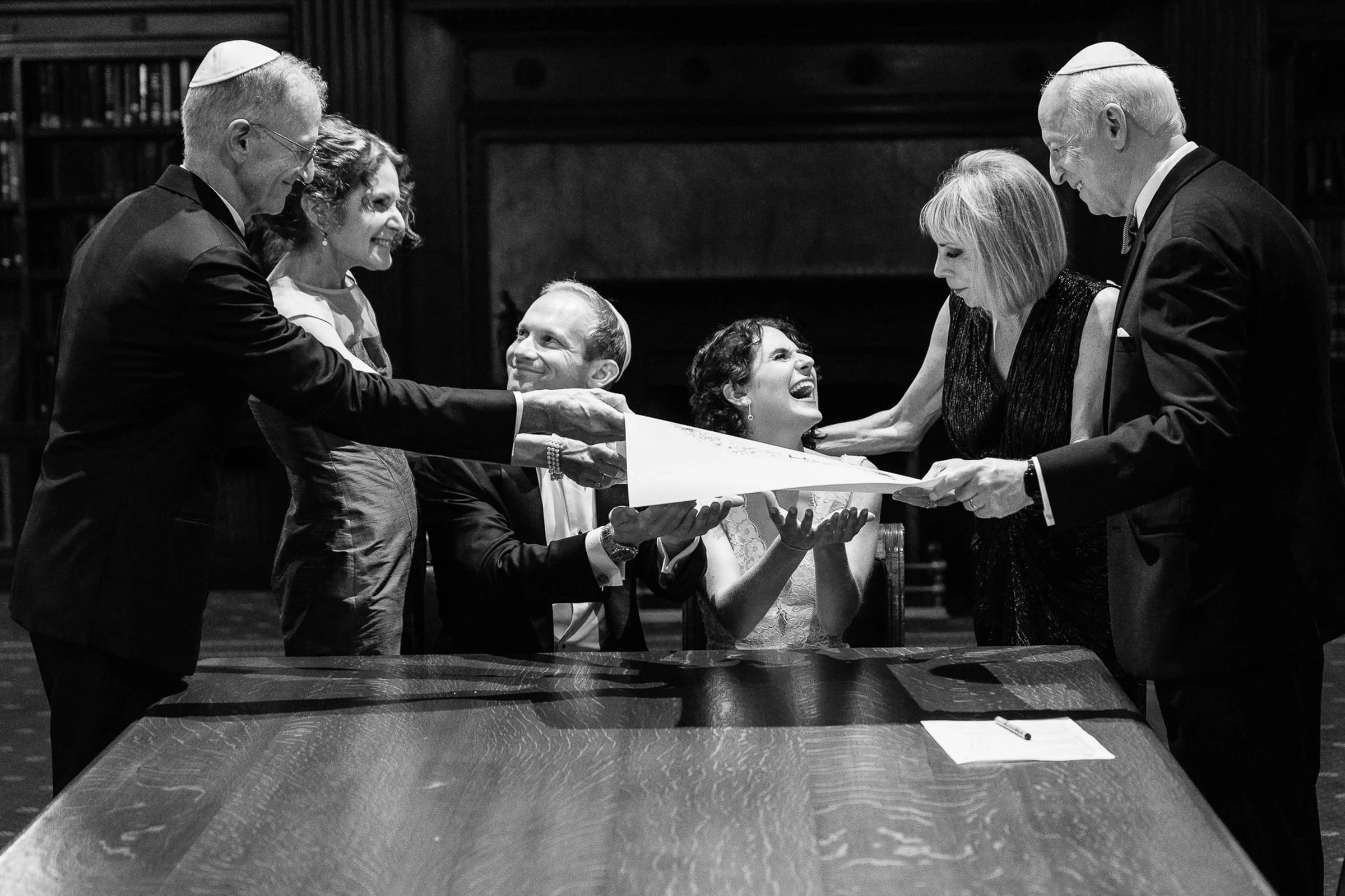 Family gathered around the table for the signing of the ketubah, in black and white